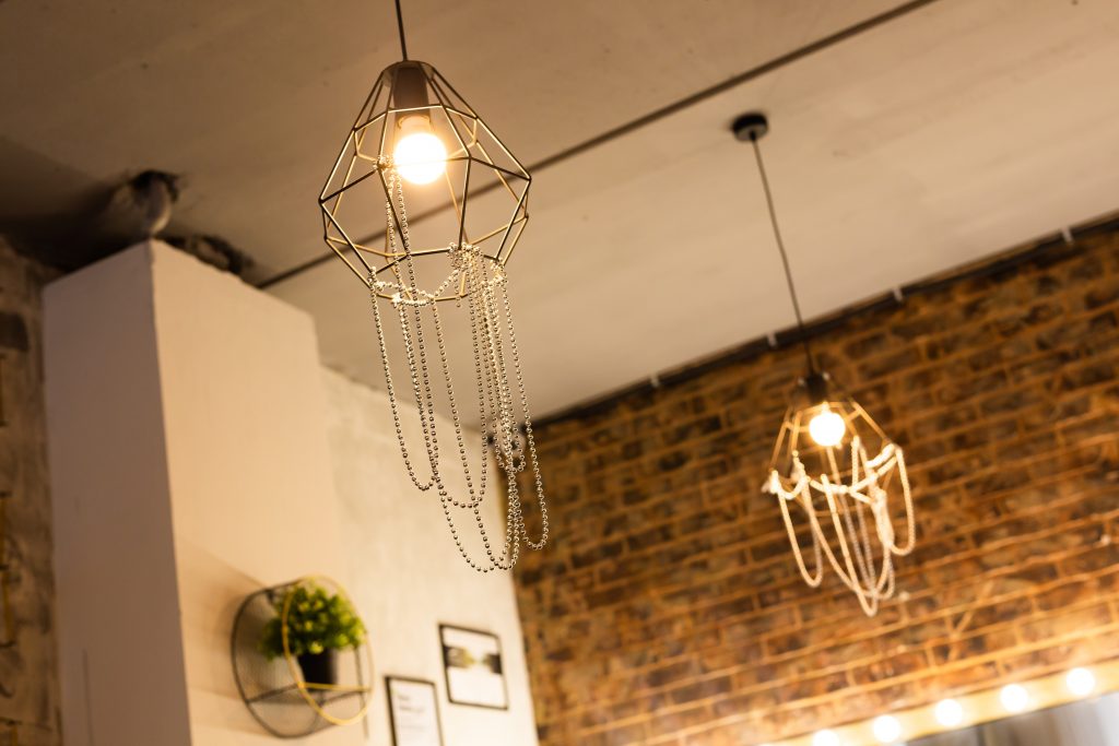 Two hanging light fixtures with metal parts as part of home decor in a brick walled living room. 