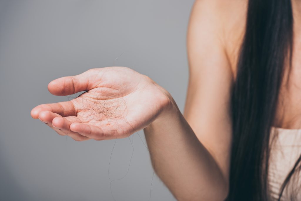 A woman with long hair holding a bunch of fallen hair strands in her palm, demonstrating hair loss and hair fall.