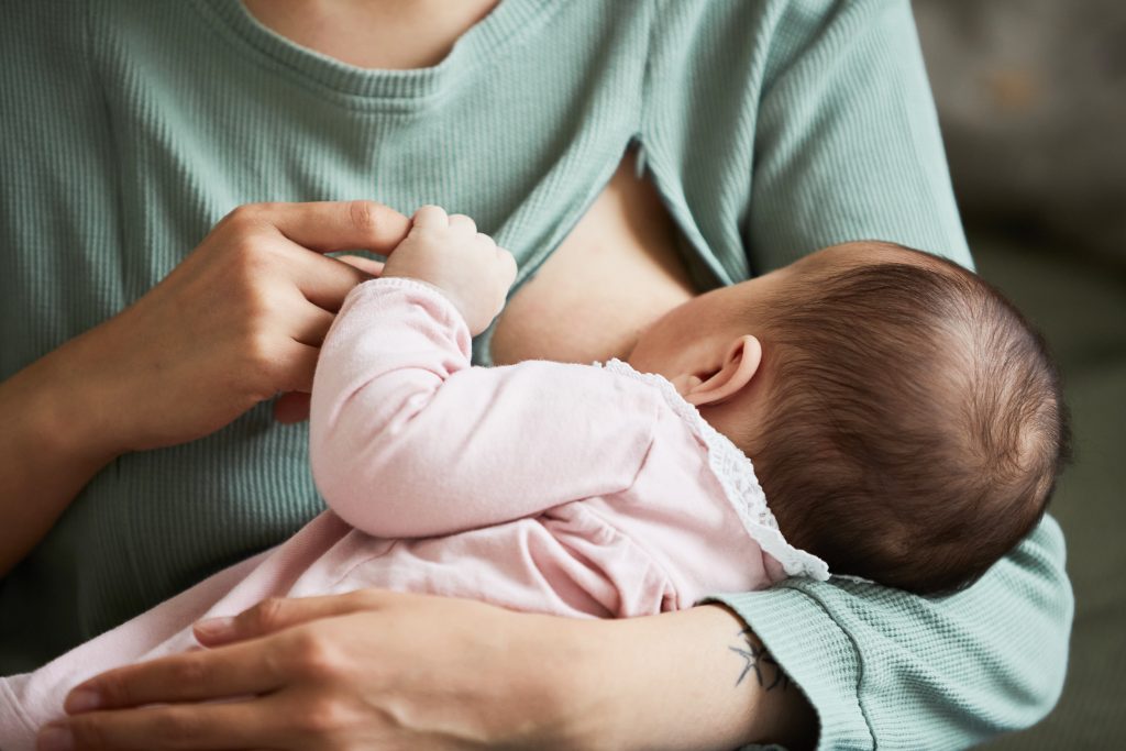 A mother breastfeeding her baby and holding her hand. Breastmilk is one of the most important baby foods. 