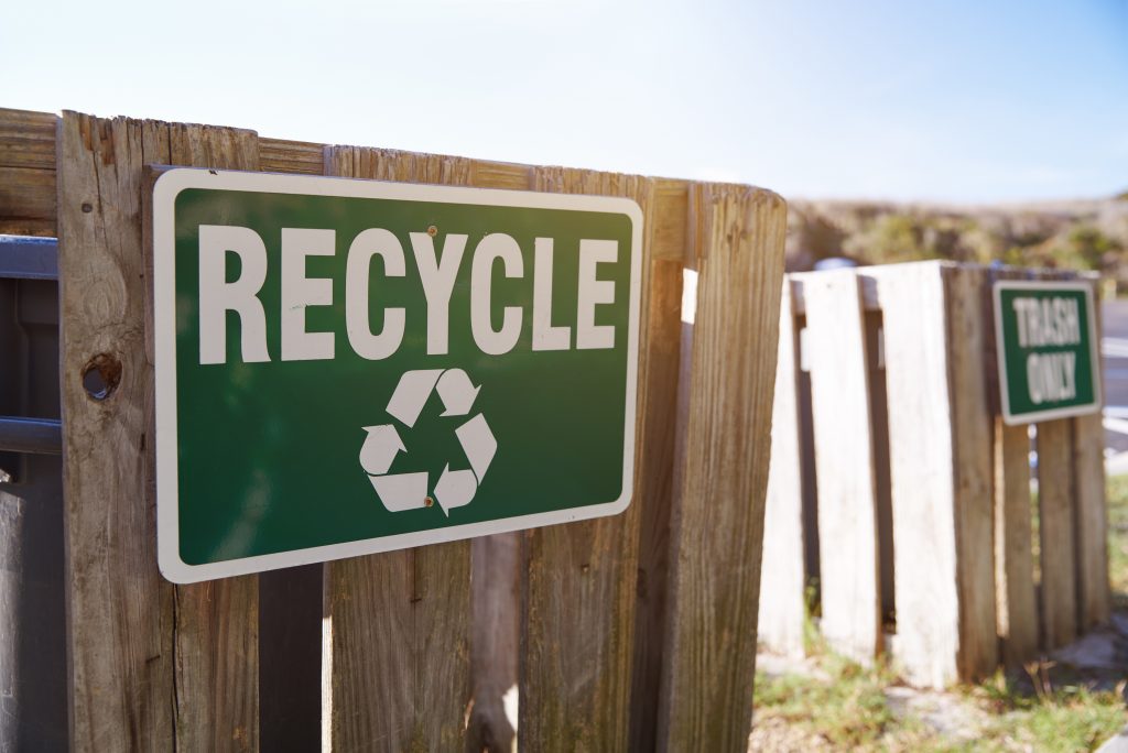 A sign on a trash bin with the term recycle on it