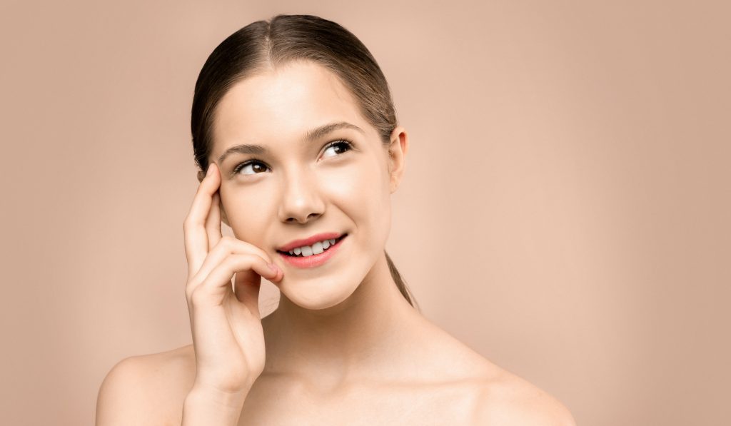 A woman with clear, healthy, and beautiful skin against a beige background. Concept of skin care, skin care, tips, healthy skin.