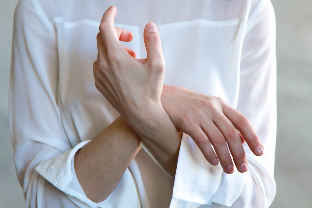 A woman wearing a white top crosses her arms. Concept of relaxation, connecting with your mind & body, and yoga.